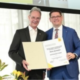 Zwei Männer halten zusammen eine Ehrenurkunde in einem festlichen Raum.
ZVEH-Präsident Stefan Ehinger (r.) mit Hans Auracher, langjähriger ZVEH-Vizepräsident und Vorsitzender der ArGe Medien im ZVEH. (Fotos: ArGe Medien im ZVEH)